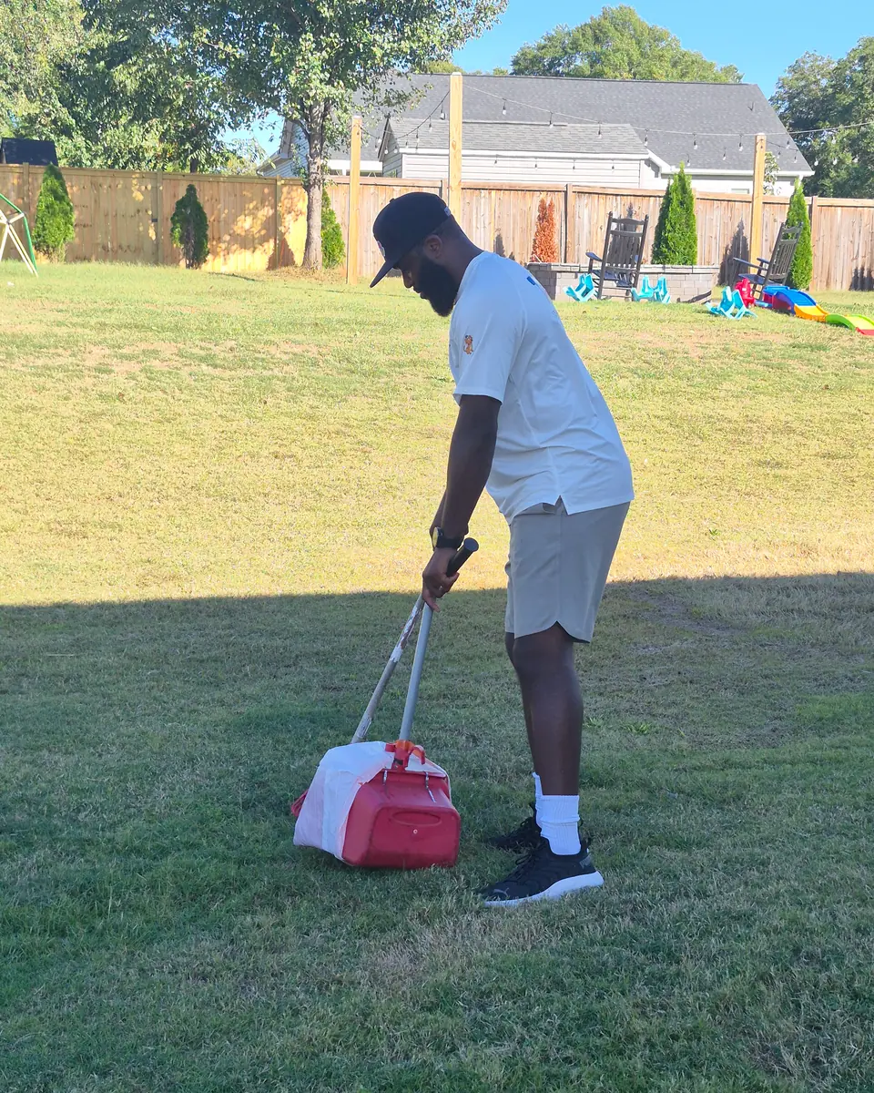 A Scoop Crew team member scooping a yard with a rake and collection pan