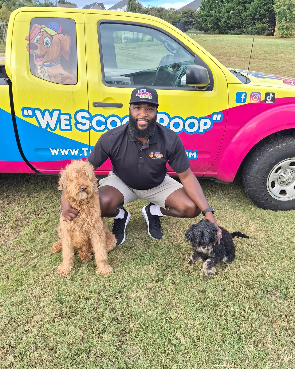 A Scoop Crew team member with two dogs beside the branded truck